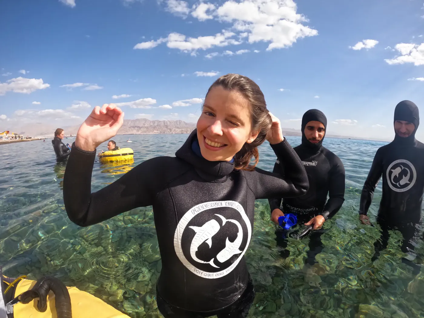 משתתפת מחייכת בחליפת צלילה של Freedive Eilat במים הרדודים
